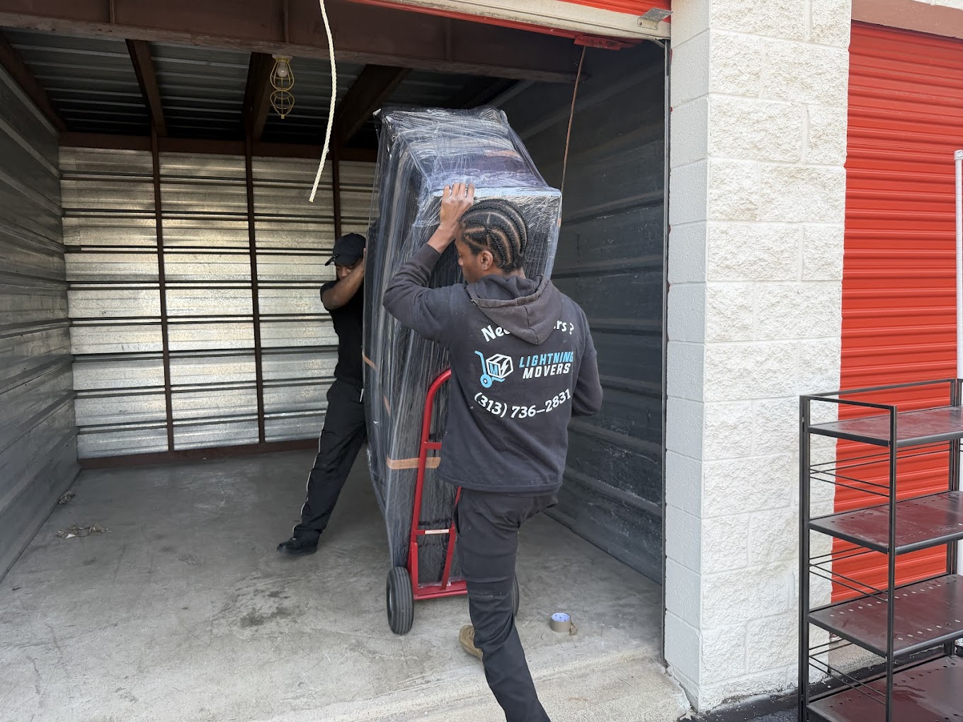 Lightning Movers crew moving a wrapped item on a dolly into storage